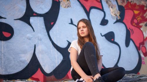 Full length of woman standing against graffiti wall