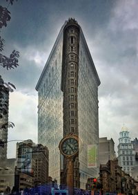 Low angle view of skyscrapers against cloudy sky