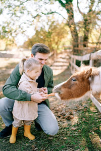 Side view of young woman with horse on field