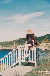 Woman standing by railing against sea