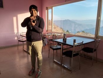 Full length of man standing by glass window on table