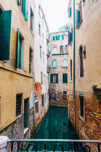 Buildings by canal against sky