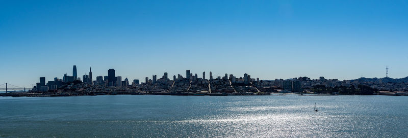 Panoramic view of sea and buildings against clear blue sky
