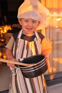 Portrait of boy wearing chef costume while standing at home