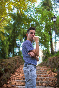 Young man looking away while standing on land