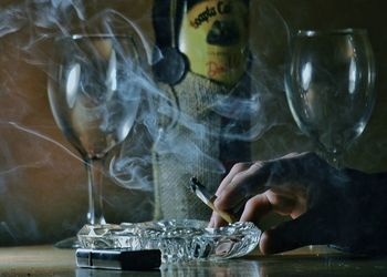 Close-up of holding cigarette while sitting on table