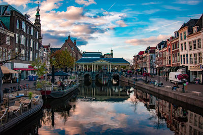 Canal amidst buildings in city against sky