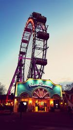 Ferris wheel in city against clear sky at dusk