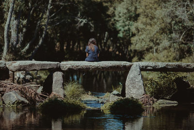 Rear view of woman sitting on bridge