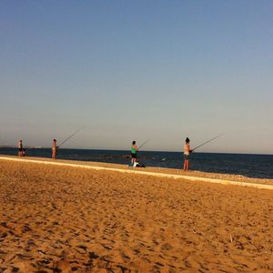 People at beach against clear sky
