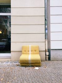 Abandoned couch against wall on footpath