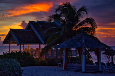 Gazebo by swimming pool against sky during sunset