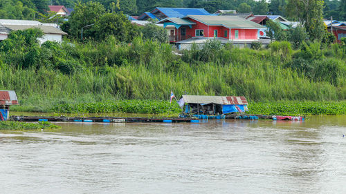 Houses by river against buildings