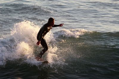 Woman surfing in sea during sunset