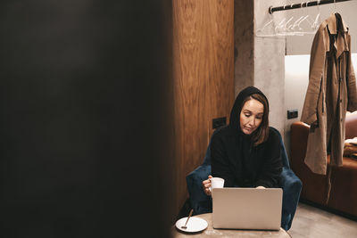 Adult confident serious smiling business woman freelancer working in a cafe using a laptop and phone