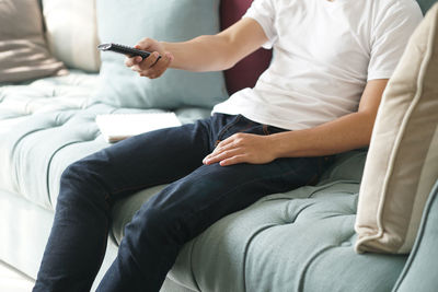 Midsection of man sitting on sofa at home