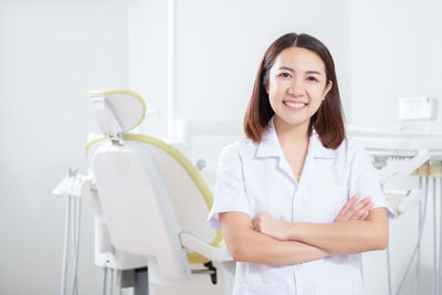 Portrait of smiling dentist standing in medical clinic