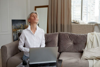 Businesswoman meditating during work from home in living room