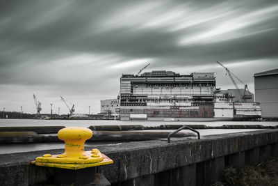 Yellow bridge over city against sky