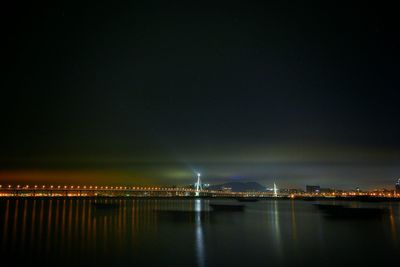 Illuminated bridge over river against clear sky at night