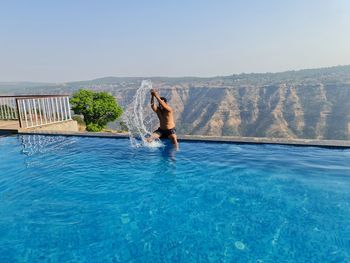 Man surfing in swimming pool against clear sky