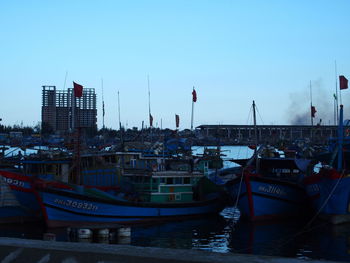 Boats in harbor against clear sky