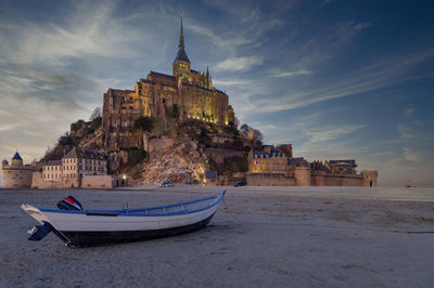 Close up of mont saint michel on sunset with boat in the foreground sand