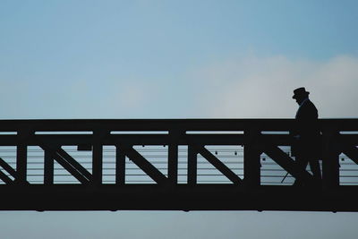 Side view of silhouette man walking on footbridge at sunset