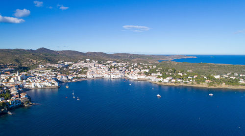Aerial view of town by sea against blue sky