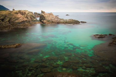 Rocks in sea against sky