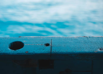 Close-up of rusty metal against blue wall