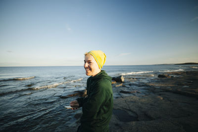 Smiling woman using phone on coast