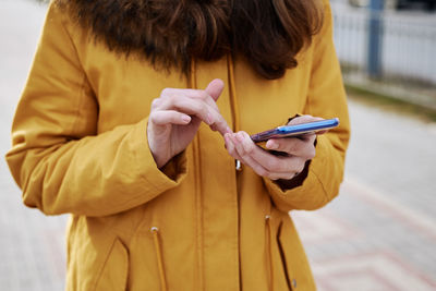 Midsection of woman holding mobile phone