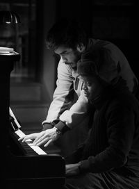 Young male musician teaching piano to woman