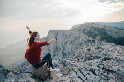 Full length of young woman on rock against sky