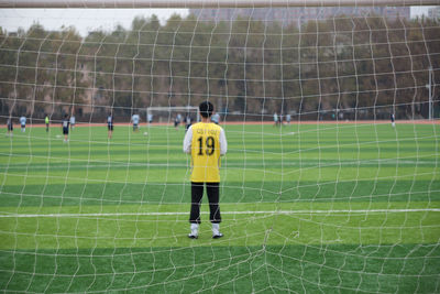 Rear view of man playing soccer on field