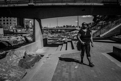 Woman walking on street by bridge in city