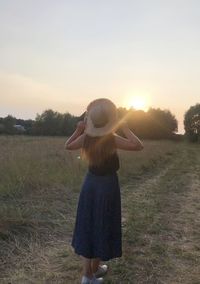 Full length of woman standing on field against sky during sunset