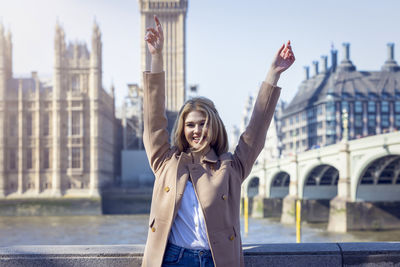 Portrait of young woman standing against buildings