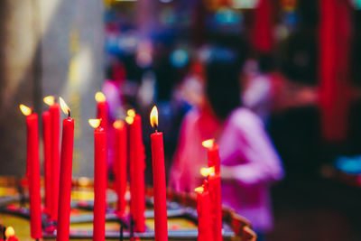 Close-up of illuminated candles in temple against building