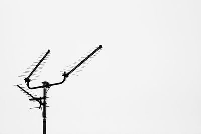 Low angle view of silhouette telephone pole against clear sky