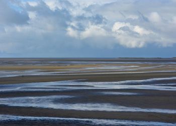 Scenic view of beach against cloudy sky