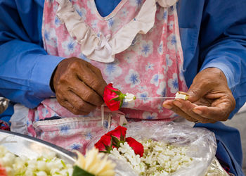 Midsection of woman making garland