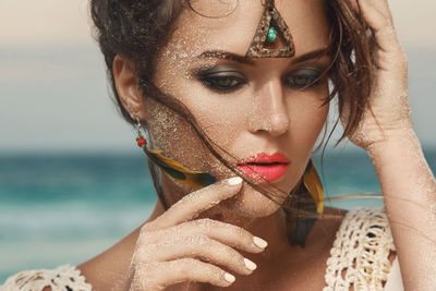Close-up of beautiful woman with sand on face