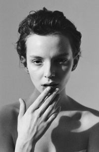 Close-up portrait of young woman smoking over white background