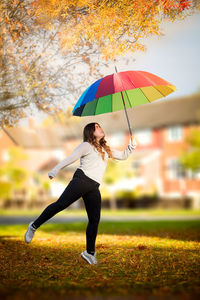 Woman with umbrella against trees during autumn