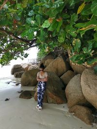 Rear view of woman sitting on rock