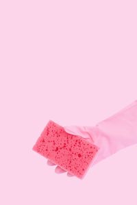 Close-up of hand holding pink petals against white background