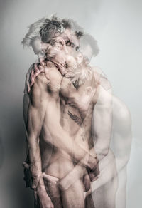 Digital composite image of shirtless gay men embracing against gray background