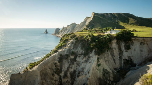 White house build on the cliff with cape and ocean in background,cape kidnappers trail, new zealand